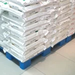 Warehouse application photo showing bags of flour stacked on blue flat-top plastic pallets protecting soft packaging from damage.
